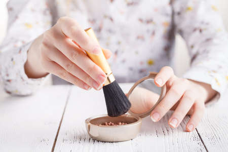 applying cosmetic with a big brush. Girl gets blush on the cheekbones. Powder, rougeの写真素材