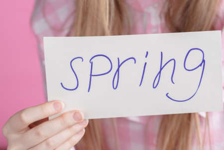 Words spring in hands of young female in pinkの写真素材