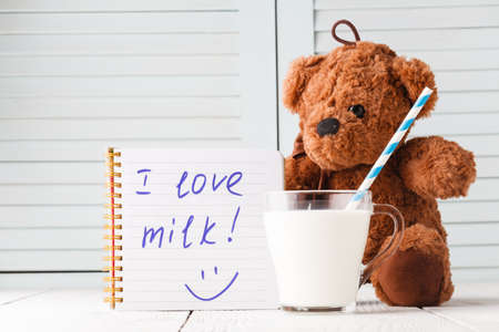 Teddy bear with milk drain on a wooden background