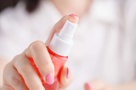 cosmetics, body parts and beauty concept - close up of woman hands spraying perfumeの写真素材