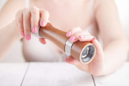 Pepper mill close up in female handsの写真素材