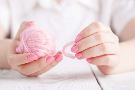 Knitting yarn twisted in clews on wooden background, light pinkの写真素材