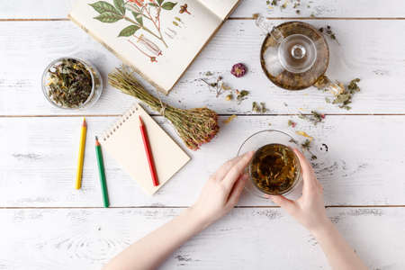 Overhead view of various sorts of tea. Flavoured with Assorted Herbs, an apple, rose with a teapot and a teacup on a rustic tableの写真素材