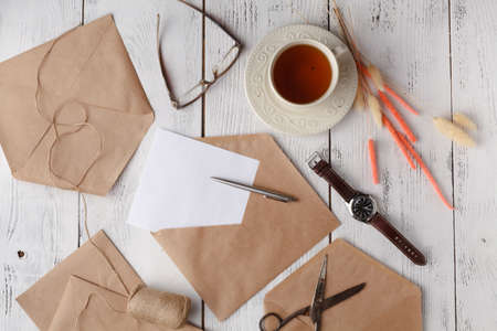 Autumn background: dried flowers and plants with blank stationary template / empty paper card in craft rustic envelope on white. Top view. Flat lay.の写真素材