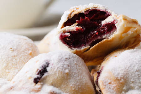 Delicious rustic pastries filled with berry on a ceramic plate on a wooden background.