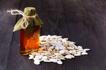 Virgin pumpkin oil in small bottle on wooden tableの写真素材