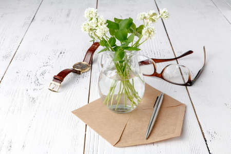 white clover in a glass jug on wooden table