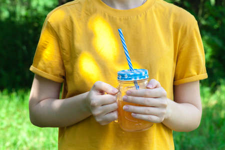 Closeup of glass jar with orange juice in woman's hand, detoxの写真素材