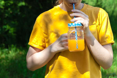 Closeup of glass jar with orange juice in woman's hand, detoxの写真素材
