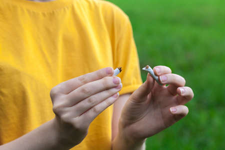 Tobacco addiction. Nicotine smoke. Girl brakes cigarette. Unhealthy, danger, bad, narcotic habit....