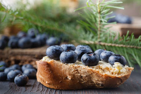 Fresh bread with blueberry jam and fruits on a rustic table