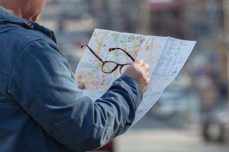 Tourist holding map paper with finding location for travel in city