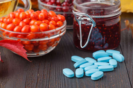 Autumn healthy beverages concept. Cup of tea with autumn berries sea buckthorn, viburnum and fall...