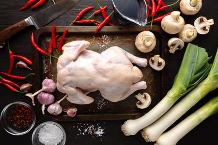 Raw uncooked chicken, drumsticks on wooden board, meat with ingredients for cookingの写真素材