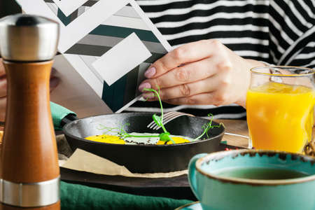 Tourist's english Breakfast in cooking pan with fried eggs, sausages, bacon, toasts and coffee