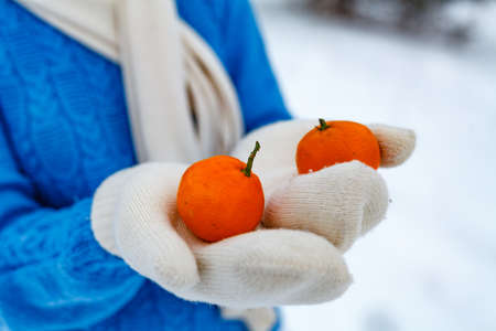 Woman wearing glove holding fruits on winterの写真素材