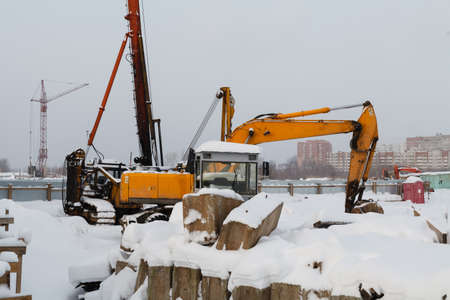 Construction site for the laying of new canals and pipes in front of a large, ugly apartment building with lots of cheap apartments in winterの写真素材