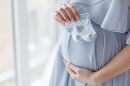 Small shoes for the unborn baby in the belly of pregnant womanの写真素材