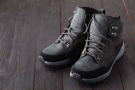 Dark boots with shoelace on wooden background