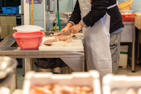 Vendor cutting fish. A typical scene at the traditional fish market