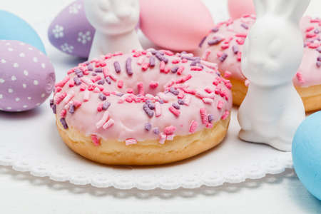 stylish easter donuts and painted eggs on rustic wooden background top view with candle yellow...