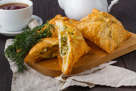 Puff pastry triangles filled with feta cheese and spinach on wooden tableの写真素材