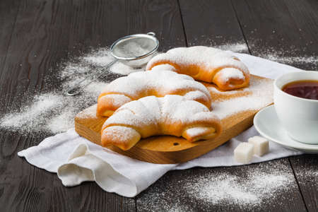 Sugar powder is poured onto a freshly baked croissanの写真素材
