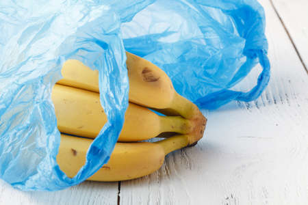 Produce in single use plastic bags and plastic free reusable shopping bags on a wooden surface in nature. Zero waste lifestyleの写真素材