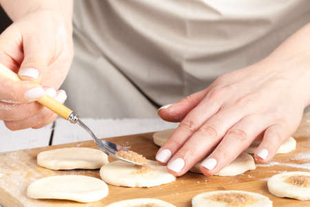 cooking and home concept - close up of hands making cookies from fresh dough at home の写真素材