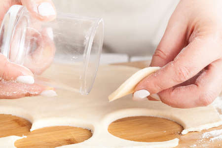 cooking and home concept - close up of hands making cookies from fresh dough at homeの写真素材