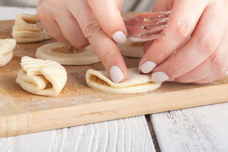 cooking and home concept - close up of hands making cookies from fresh dough at homeの写真素材