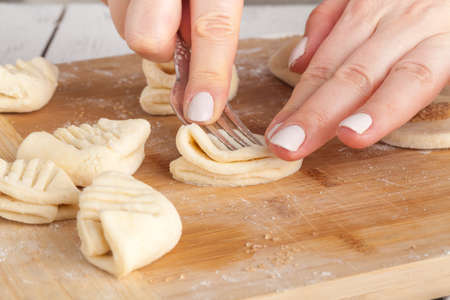cooking and home concept - close up of hands making cookies from fresh dough at homeの写真素材