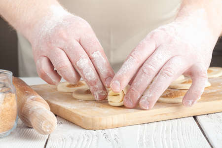 cooking and home concept - close up of hands making cookies from fresh dough at homeの写真素材