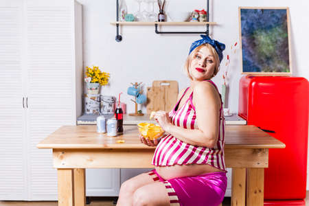 change of taste preferences during pregnancy, the pregnant model gladly eat potato chipsの写真素材