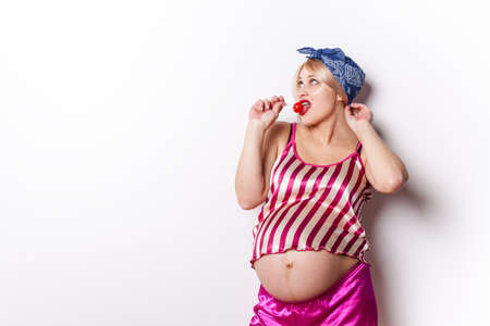 Portrait of happy beautiful pregnant woman licking chupa chupsの写真素材