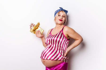 happy cute pregnant woman standing isolated over white background eating chocolateの写真素材