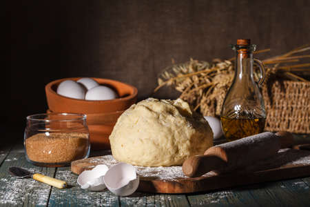 Prepare dough for making homemade dumplings or noodles on a brown wooden table in a rustic kitchenの写真素材