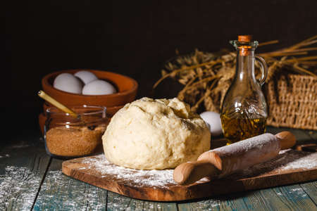 Ingredients for baking croissants - flour, wooden spoon, rolling pin, eggs, egg yolks, butter served on wooden backgroundの写真素材