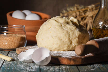 Ingredients for baking croissants - flour, wooden spoon, rolling pin, eggs, egg yolks, butter served on wooden backgroundの写真素材