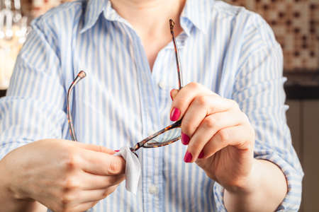 close up spectacles with girl hand holding glasses on wood desk. Release concept. spectacles selective focus.の写真素材