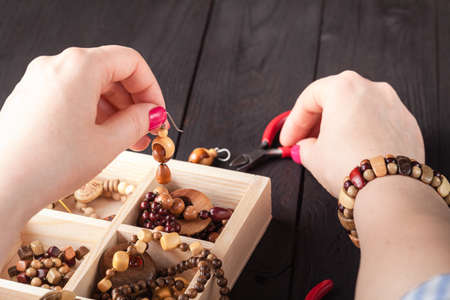 Making of handmade jewellery. Box with beads on old wooden table.の写真素材
