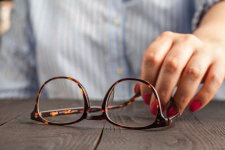 female hand holding a brown framed glassesの写真素材