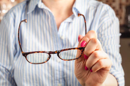 female hand holding a brown framed glassesの写真素材