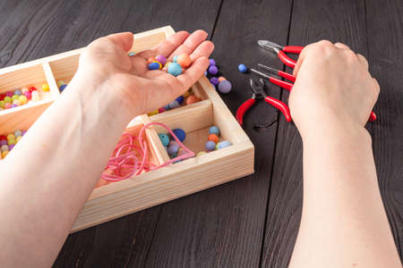 Woman makes an ornament from beads. Mix color beads. Hobby conceptの写真素材
