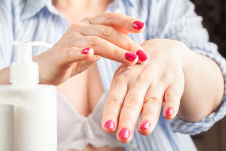 Application of moisturizer. Woman's hands with a white tube of creamの写真素材