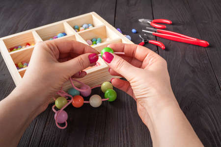 Woman makes an ornament from beads. Mix color beads. Hobby conceptの写真素材