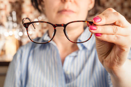 female hand holding a brown framed glassesの写真素材