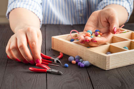 Making of handmade jewellery. Box with beads on old wooden table.の写真素材