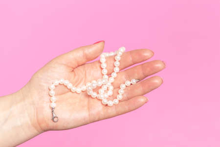 White pearl necklace on the woman's handの写真素材