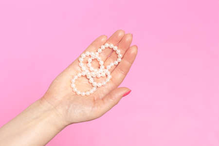 White pearl necklace on the woman's handの写真素材